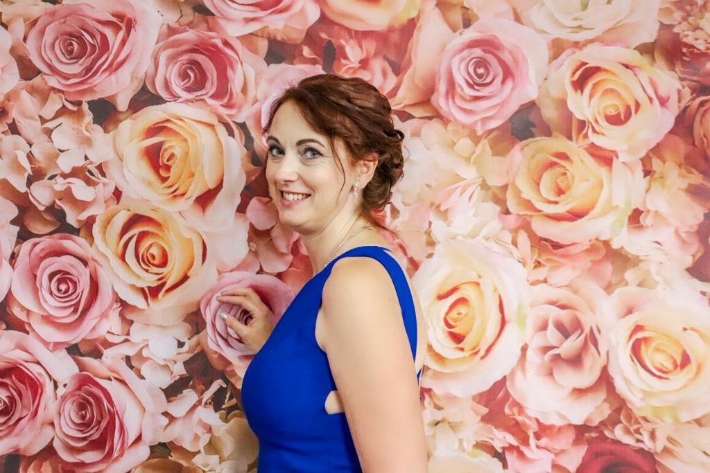 Krásna žena v strednom veku v kráľovsky modrých spoločenských šatách pred kvetinovým vynilovým fotopozadím rozmeru 290x230 cm